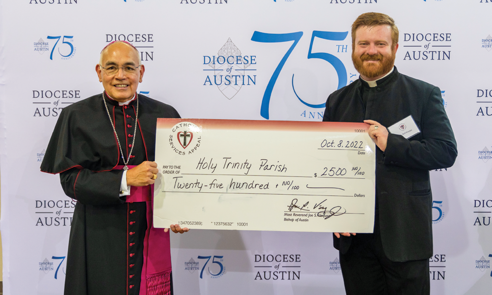 Father Payden Blevins, pastor of St. Joseph in Mason and Holy Trinity in Llano, accepted checks for each parish thanks to the Catholic Services Appeal Parish and School Grant program